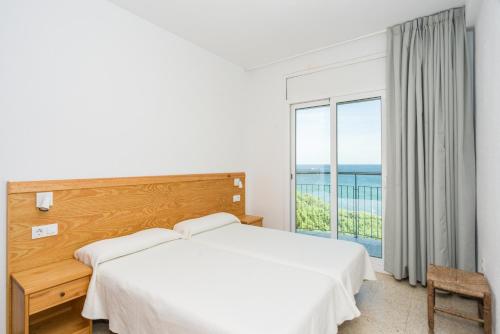 布拉内斯Apartamentos Blanes-Condal Costa Brava的卧室设有白色的床和大窗户