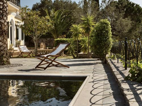 扎金索斯镇Almeira 4acre Estate, for Unparalleled Seclusion, By ThinkVilla的坐在池塘旁的椅子,在院子里
