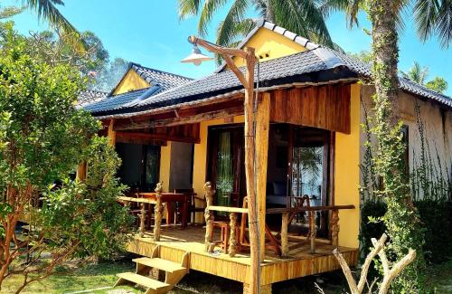 富国Dugong Resort Phu Quoc的黄色的小房子,设有门廊和桌子