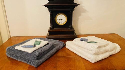 林茨LINZ CITY CENTER - Historisches Apartment & Refugium的木地板上配有2条毛巾和1个钟