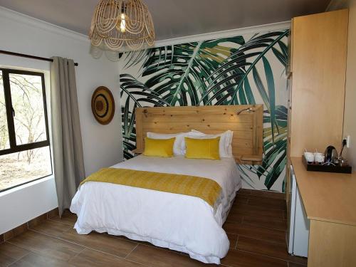 布拉瓦约The Musketeers Lodge的一间卧室配有一张带黄色枕头的床和壁画