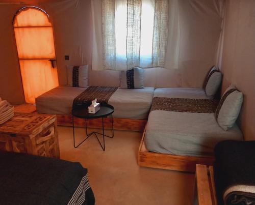 AdrouineNight sky luxury camp的客房设有两张床、一张桌子和一扇窗户。