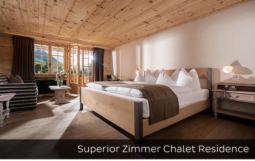 格施塔德Hotel Arc-en-ciel Gstaad的一间卧室设有一张带木制天花板的大床