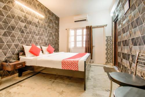巴特那OYO Flagship 78696 Hotel Kamini的一间卧室配有一张带红色枕头的床和一张桌子