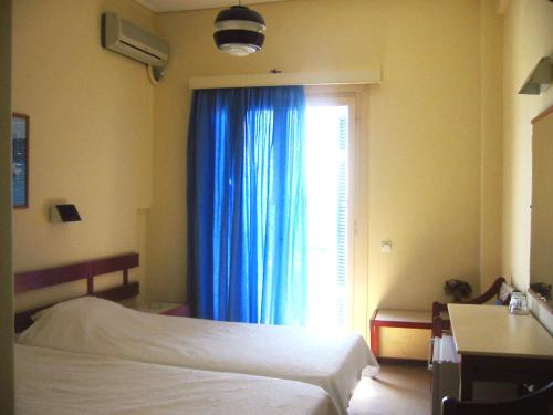 爱琴娜岛Hotel Avra的一间卧室配有床和蓝色窗帘的窗户