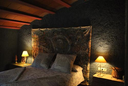 科尔努德利亚Masia El Riscle - Moli Del Pont的一间卧室配有一张大床和两盏灯