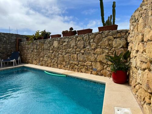 休吉让4 Bedroom Holiday Home with Private Pool & Views的石头墙前的游泳池