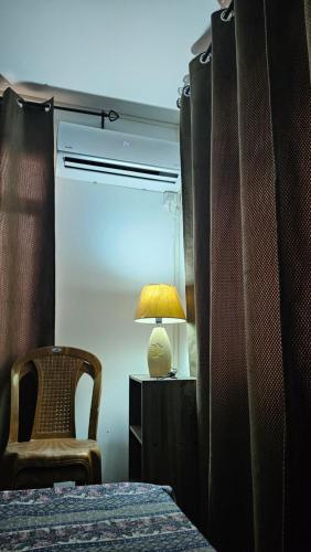 Petit RaffraySK Residence的一间卧室配有一张床、一盏灯和一把椅子