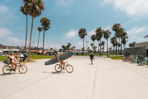 洛杉矶Private room in venice beach的骑着自行车的人,带冲浪板