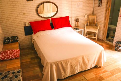 里约热内卢Casa da Cacaia e do Henrique的一间卧室配有一张带红色枕头和镜子的床