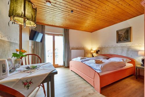 奥巴拉马高Gästehaus Eder Oberammergau的一间卧室配有一张大床和一张桌子及书桌。