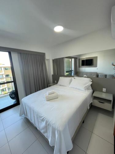 伊波茹卡Flat com vista para piscina principal的卧室配有一张白色大床和两条毛巾