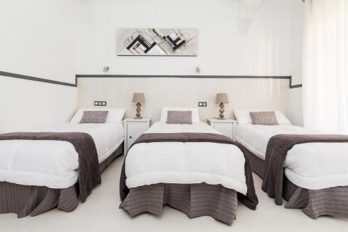马德里63号大道旅馆的白色墙壁的客房内的三张床
