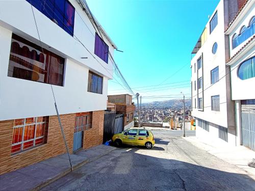 阿雷基帕Fernanda apartment的停在两栋建筑之间街道上的黄色汽车