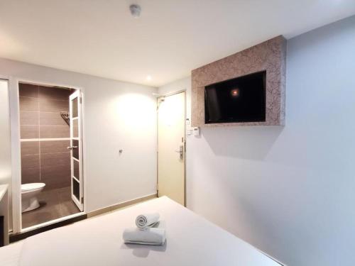吉隆坡Mozu Hotel Sri Hartamas的卧室配有一张床,墙上配有电视。
