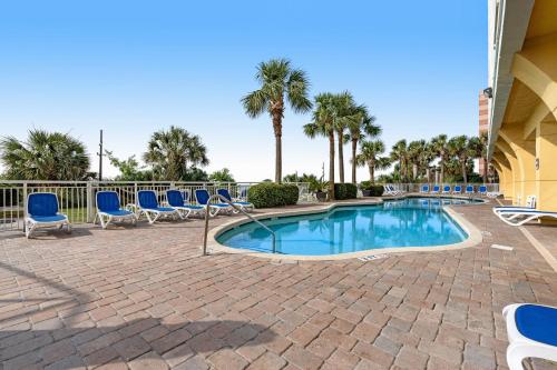 默特尔比奇Camelot by the Sea - Oceana Resorts Vacation Rentals的一个带蓝色椅子的游泳池,棕榈树