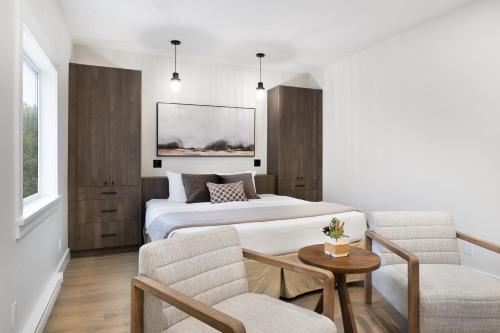 伦弗鲁港West Coast Trail Lodge的酒店客房带一张床、一张桌子和椅子