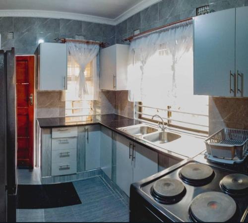 利文斯顿Scolt Apartments Livingstone的厨房配有白色橱柜和炉灶烤箱。