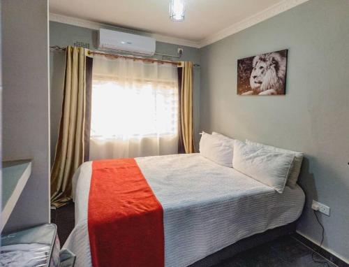 利文斯顿Scolt Apartments Livingstone的一间卧室配有一张带彩色毯子的床