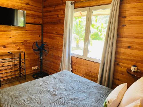 莫雷阿Bungalow KURA的一间卧室设有木墙和一张带窗户的床