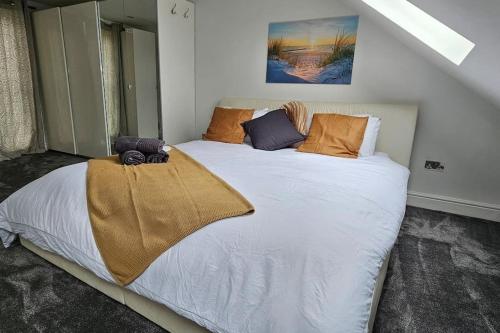 The HydeCozy & Elegant 4 Bedroom Home Near Wembley的卧室配有带橙色枕头的大型白色床