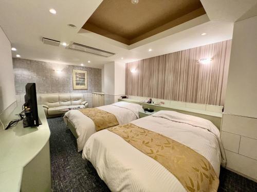 武雄市SKY Lmine Takeo LOVEHOTEL的酒店客房设有三张床和电视。