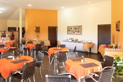 卡兰卡斯Pousada Além das Formas的用餐室配有橙色桌椅