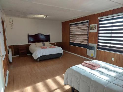 蓬塔阿雷纳斯Alojamiento Punta Arenas的酒店客房设有两张床和窗户。