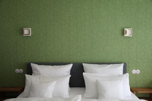 GeisfeldLuisenhof的一张带白色枕头和绿色墙壁的床