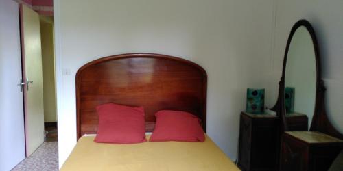 梅里尼亚克Villa Lulu的一张带木制床头板和两个红色枕头的床