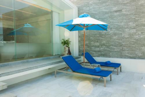 湄南海滩Explorar Koh Samui - Adults Only Resort and Spa的门廊上摆放着两把蓝色椅子和一把雨伞