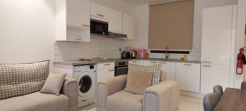 塞拉莱Maxim Hawana Salalah的厨房配有洗衣机和2把椅子