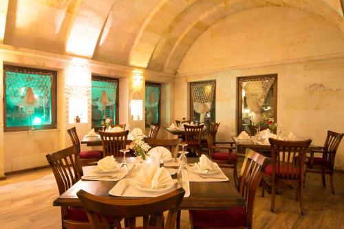 奥塔希萨尔Cappadocia Fairy Chimneys Minia Cave Hotel的大楼内带桌椅的用餐室