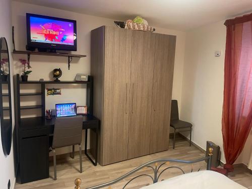 恩纳Archetto-casa vacanze的客房设有书桌和带电视的橱柜。