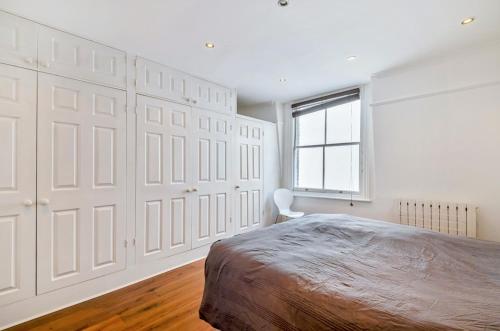 伦敦钱塞瑞之阁楼私人公寓的卧室拥有白色的墙壁、一张床和窗户
