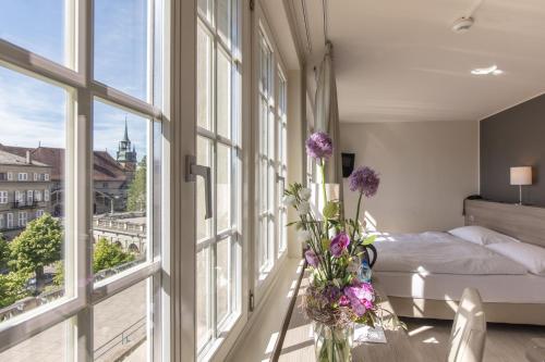 弗里堡德拉玫瑰酒店 的一间卧室设有一张床,窗户开满了鲜花