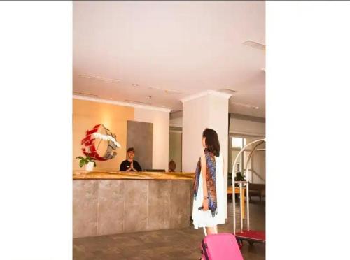 BatulicinMugiwara Hotel&Apartment的站在大厅的女人,带着手提箱