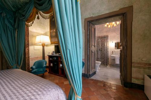 那不勒斯Palazzo Doria Napoli的一间卧室配有蓝色窗帘的床和一间浴室
