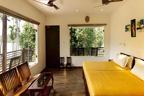 科钦Lhasa Ayurveda and Wellness Resort - A BluSalzz Collection, Kochi, Kerala的一间卧室设有一张大黄床和两个窗户。