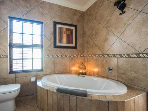比勒陀利亚Isiphiwo Village Accommodation Venue and Spa的带浴缸、卫生间和窗户的浴室
