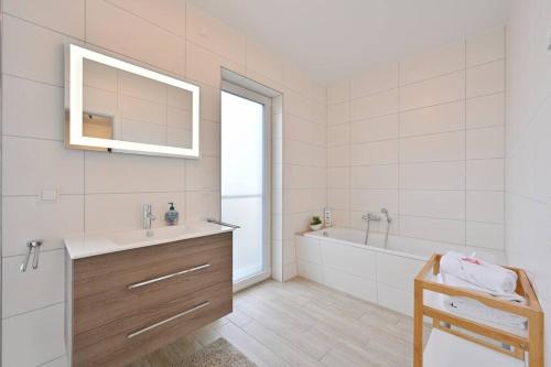 特伦特Villa Strandgut的一间带水槽、浴缸和镜子的浴室