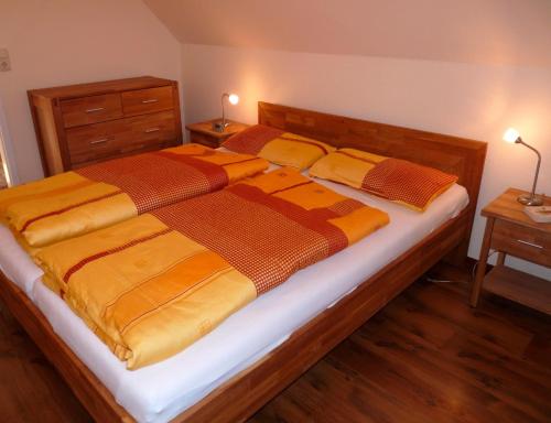 格赫伦-莱宾Ferienhaus Fleesensee的一间卧室配有一张大床,提供黄色和橙色的毯子
