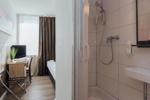 汉堡Hotel Hanseat Hamburg的带淋浴的浴室和书桌。