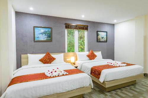 吉婆岛Cat Ba Violet Hotel的一间卧室设有两张床和窗户。