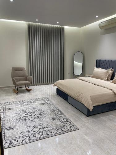 Riyadh Al Khabraشقة فاخرة دور ارضي مدخل خاص وباركنج سيارة的一间卧室配有一张床、一把椅子和地毯