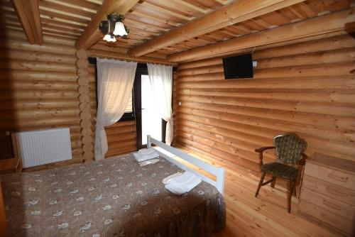 别列戈沃Садиба Арсентій的小木屋内的卧室,配有一张床和椅子