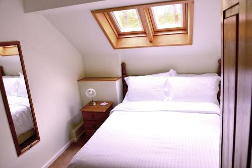 科文Hafannedd Cottage - riverside views的卧室配有白色的床和镜子