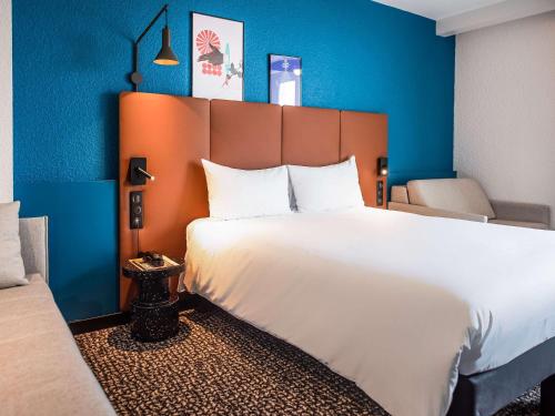 波尔尼谢ibis La Baule Pornichet Plage的卧室配有白色大床和蓝色的墙壁