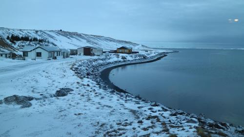 Borðeyri塔安加胡斯旅馆的一片积雪的海滩,拥有房屋和水