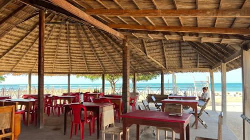 卡波德拉维拉El Viejo Moi Hospedaje & Restaurante的海滩上的餐厅,配有桌椅